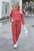 Woman wearing a relaxed cotton-linen monochrome capsule set with longline top and wide-leg pants in rust color walking outdoors
