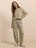 Woman wearing European minimalism relaxed khaki sweater top and trouser set with knit pocket and crew neck.