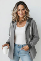 Woman wearing gray Highland Plaid Shacket with hood, white tank top, and blue jeans holding coffee cup