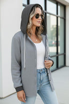 Woman wearing a gray hooded relaxed-fit Highland Plaid Shacket with button front over white top and jeans outdoors