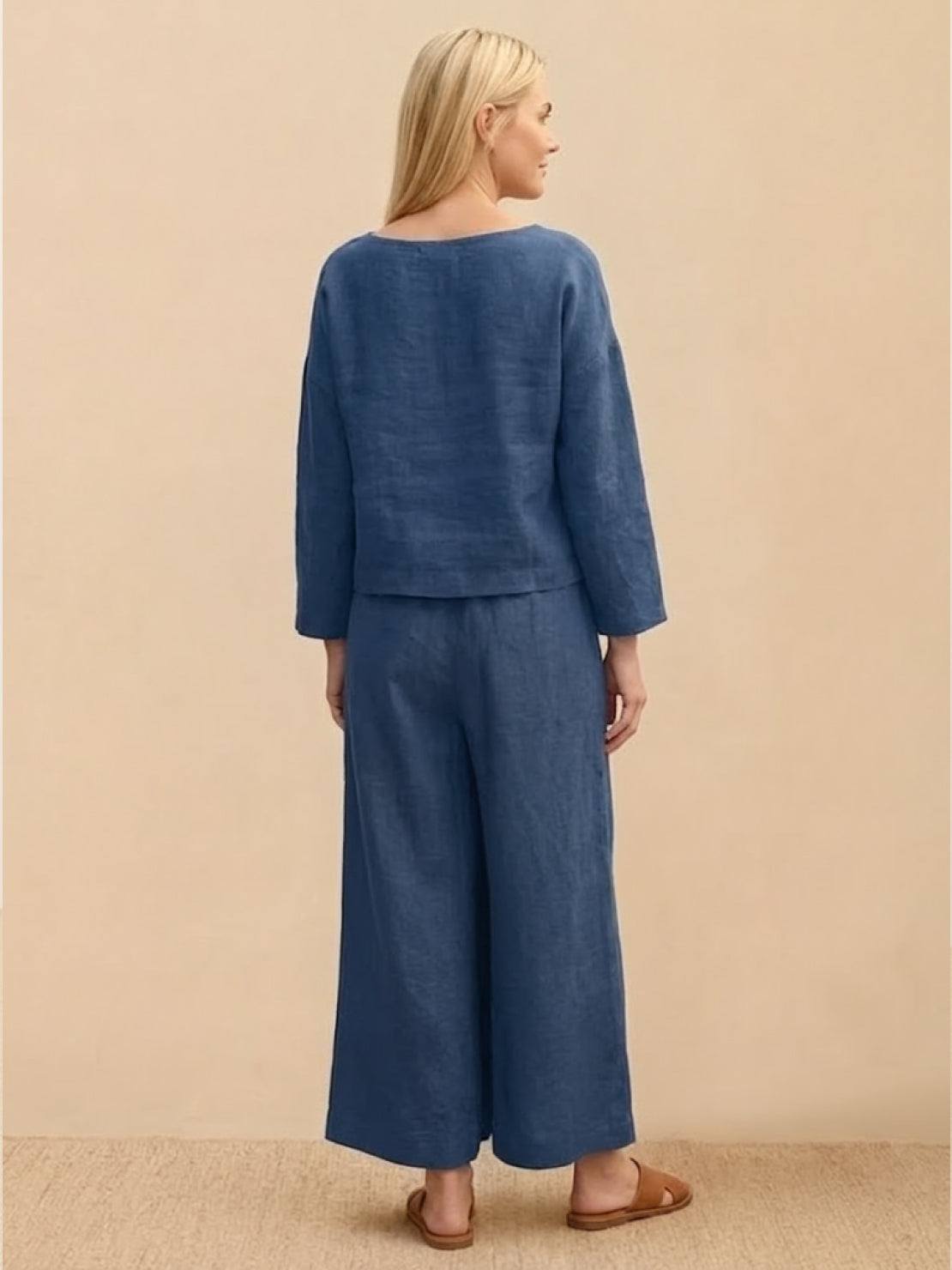 Loose solid color blue two-piece set with loose fit top and wide-leg pants on a woman standing against beige background