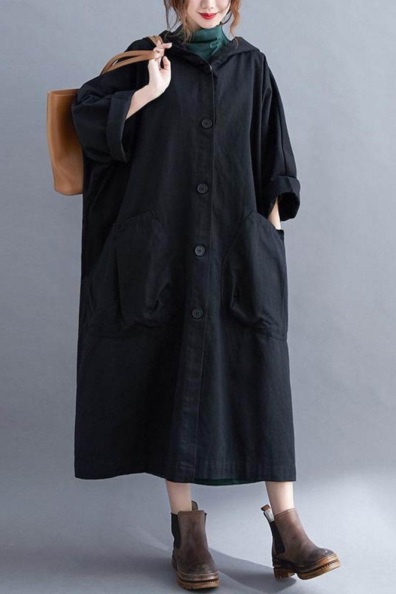 Oversized black Heritage Windbreaker Jacket with button closure and large front pockets, worn with boots and carrying a brown bag.