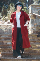 Woman wearing oversized red water resistant windbreaker jacket with hood and snap-button closure outdoors