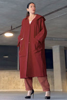 Oversized one-size water resistant windbreaker jacket with hood and large pockets in red worn by woman