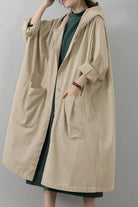 Oversized beige water resistant windbreaker jacket with hood and large front pockets for layering and protection against wind and rain