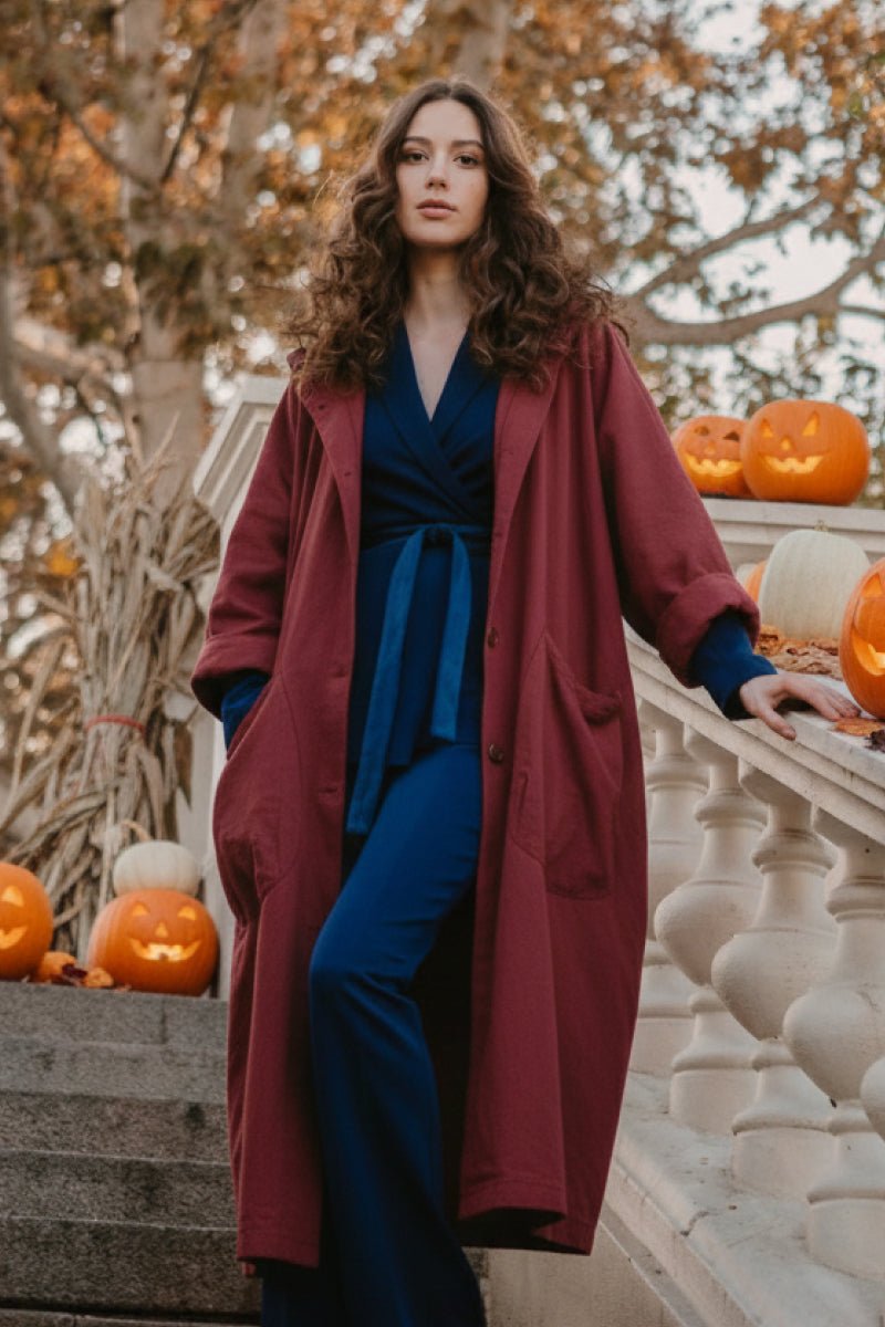 Woman wearing oversized maroon water resistant windbreaker jacket with pumpkins in background