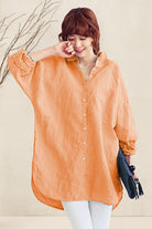 Woman wearing an oversized orange linen shirt with loose sleeves and button front