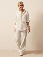 Woman wearing oversized 100% cotton shirt and wide-leg pants co-ord set in white, styled casually with rolled sleeves.
