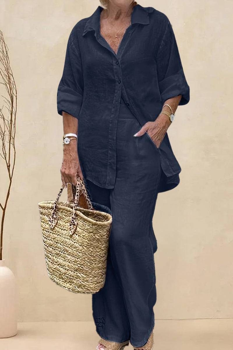 Woman wearing oversized 100% cotton shirt and wide-leg pants co-ord set in dark navy blue with rolled sleeves and carrying a woven basket bag.