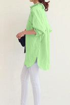woman wearing oversized light green linen shirt with rolled-up sleeves and white pants side view