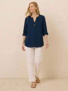 woman wearing navy pure linen age-defying button detail shirt with white pants walking indoors