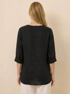 Back view of woman wearing black Pure Linen Age-Defying Shirt with rolled sleeves and relaxed fit.
