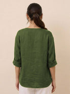 Back view of woman wearing green pure linen age-defying button detail shirt with rolled sleeves