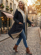 Woman wearing black sherpa-lined hooded teddy coat with jeans and brown boots walking on cobblestone street in autumn background