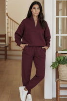 Woman wearing burgundy cotton blend tracksuit with zip neckline and relaxed fit in modern home interior