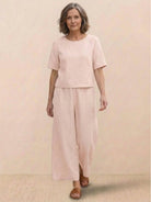 Woman wearing a loose fit co-ord set with a soft-tailored top and wide-leg bottoms in solid color