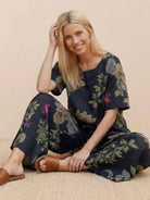 Woman wearing a loose fit co-ord set with wide-leg floral print trousers and a soft-tailored short sleeve top, styled casually with sandals.