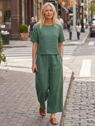 Woman walking in green loose fit co-ord set with wide-leg pants and short-sleeve top on city street