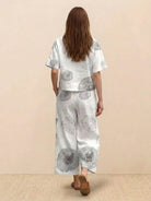 Woman wearing a loose fit co-ord set with wide-leg trousers and short-sleeve top in light fabric with circular print pattern, standing against plain background