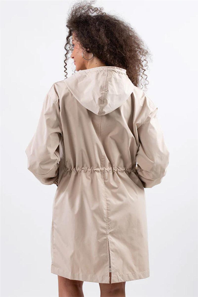 Back view of a woman wearing beige oversized Rain Couture Windbreaker with hood and adjustable waist, made of lightweight water-resistant fabric
