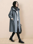 Woman wearing a trendy oversized Rain Couture Windbreaker in gray with black boots and scarf