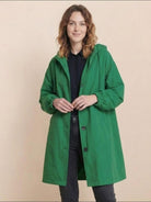 Woman wearing oversized green Rain Couture Windbreaker water-resistant jacket with hood and buttons