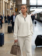 Woman wearing ultra-soft and comfy co-ord tracksuit set in beige at train station carrying handbag