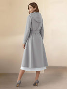 Woman wearing water-repellent rain A-line hooded raincoat with belt, elegant and weather-resistant.