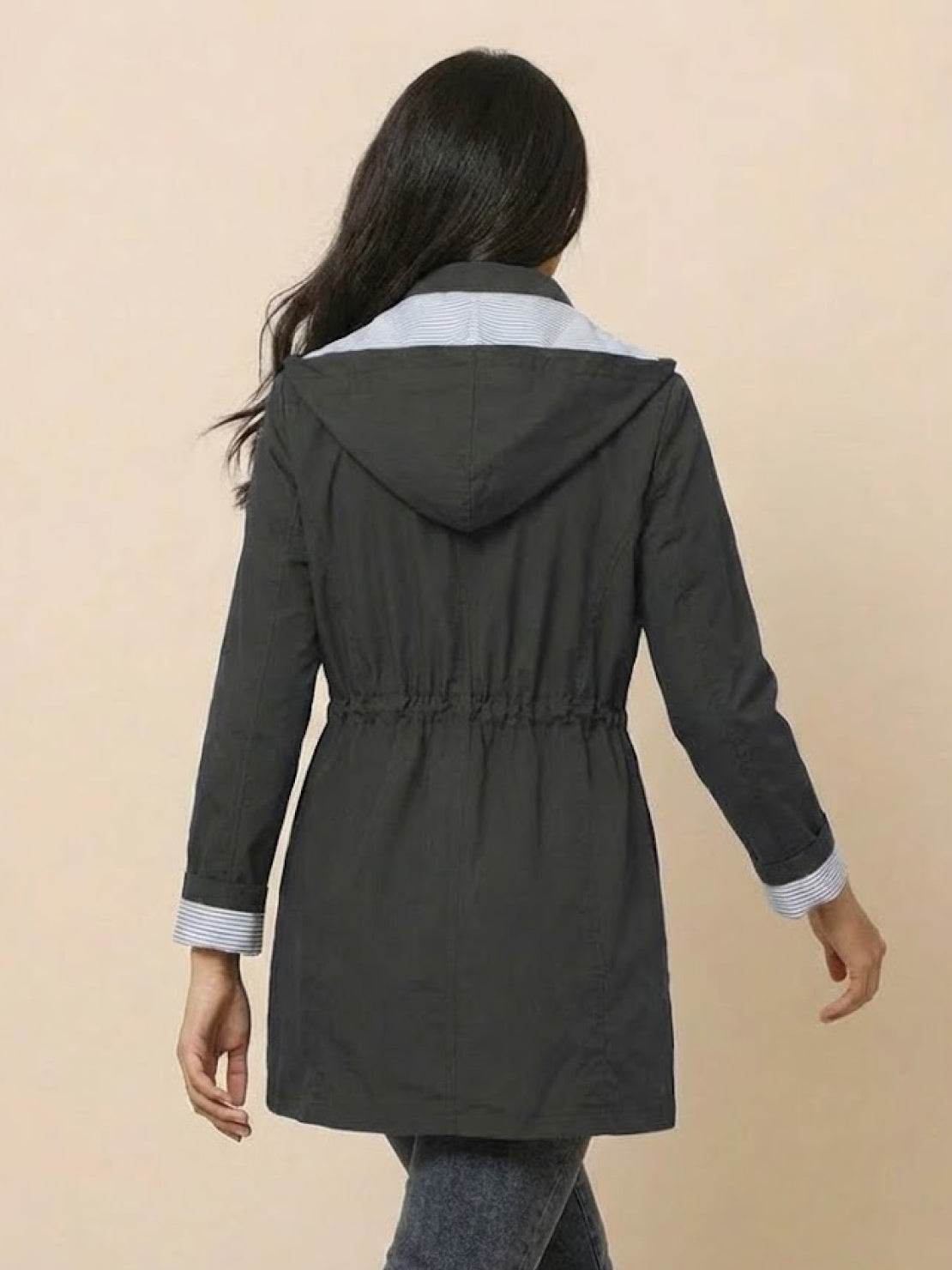 Back view of woman wearing water resistant hooded striped windbreaker jacket with adjustable waist