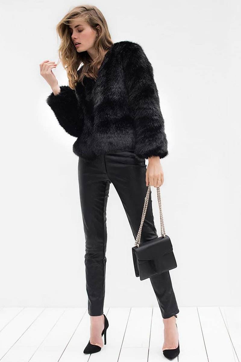 Woman wearing a bold faux fur luxe jacket with V neckline and button front closure paired with black pants and heels